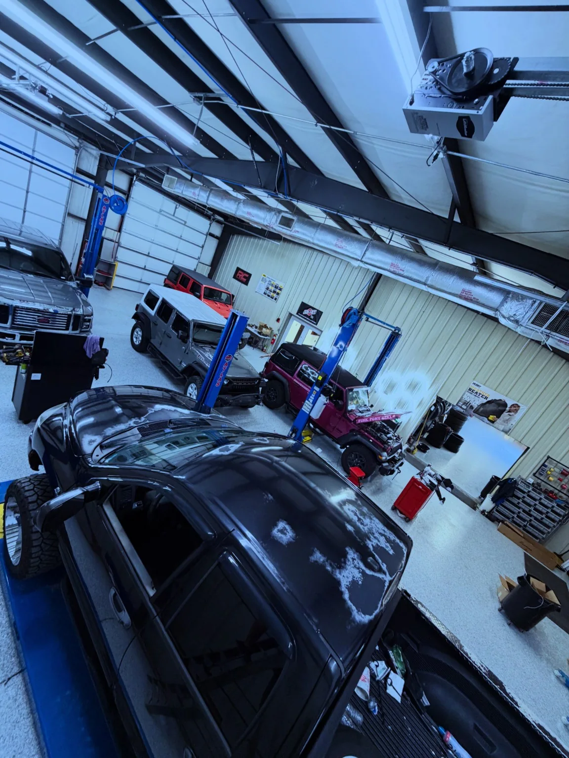 Interior automotive workshop with lift and multiple vehicles