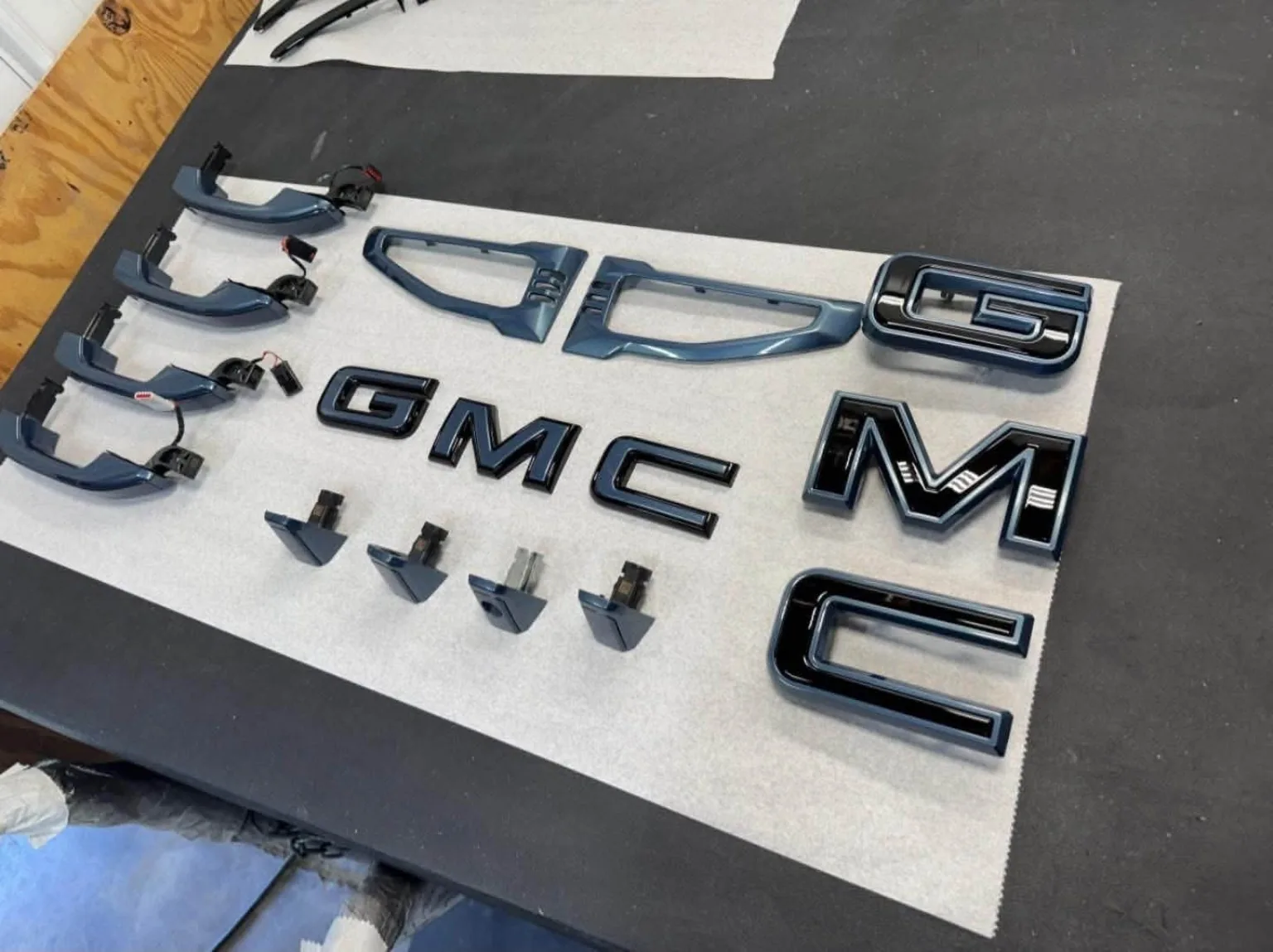 Automotive trim and GMC badges arranged on a workbench