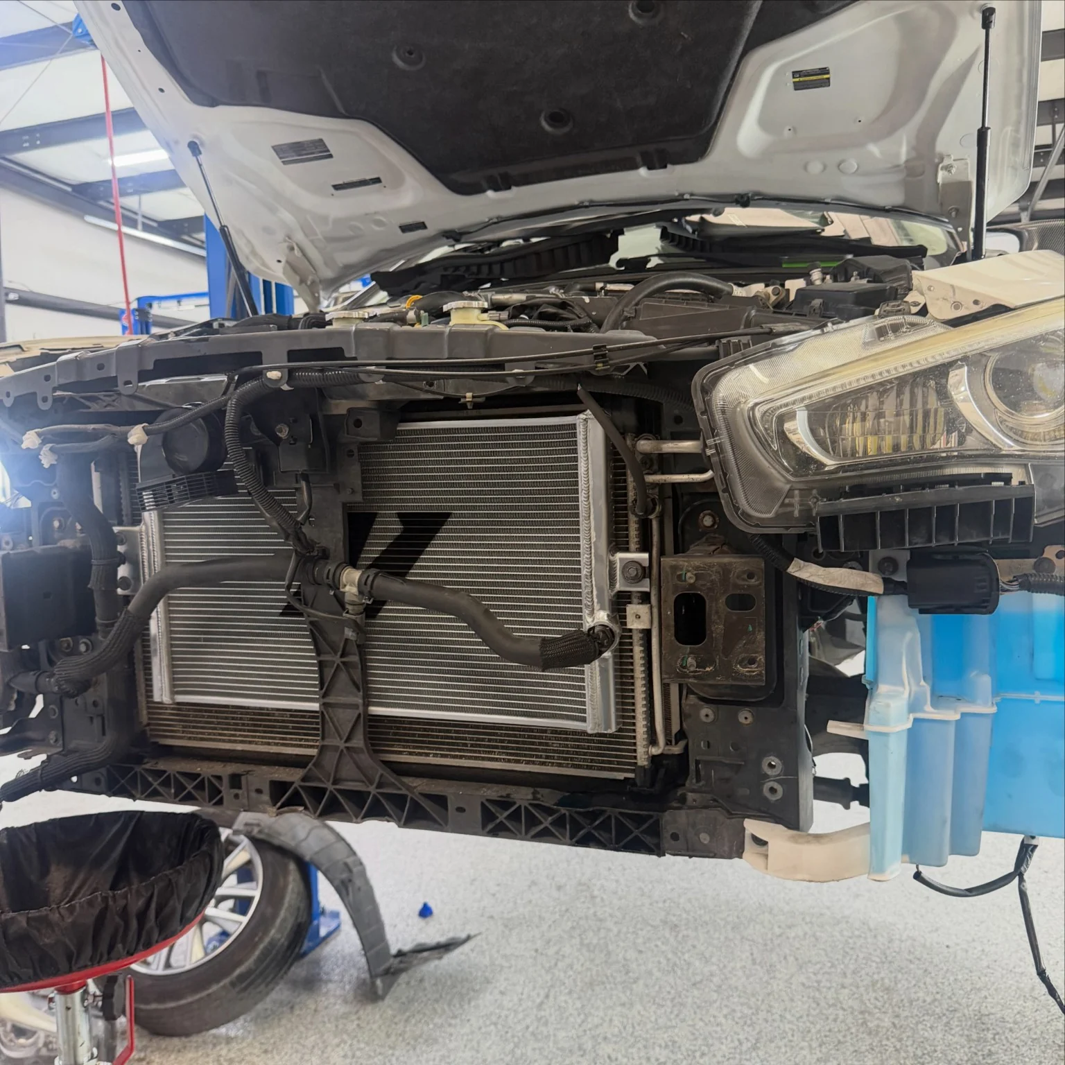 Vehicle with hood raised and front bumper removed inside the workshop
