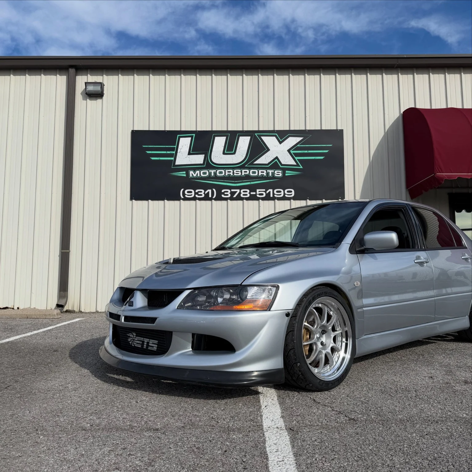 Silver Mitsubishi Lancer Evolution outside the LUX Motorsports shop